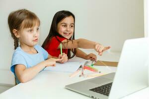 deux filles, le le plus ancien et le le plus jeune, sont engagé à une table sur une portable. photo