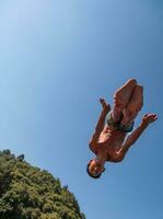 une homme dans une maillot de bain est sauter dans le l'eau photo