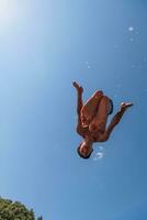 une homme dans une maillot de bain est Faire une retourner dans le air photo