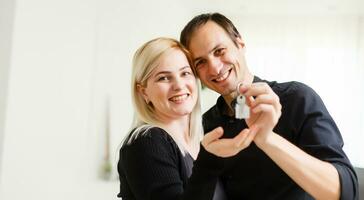 content souriant Jeune couple montrant une paire de clés de leur Nouveau maison photo