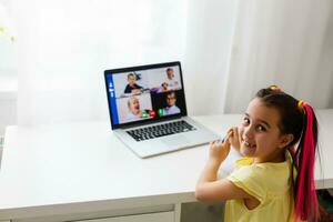 cool en ligne école. enfant en train d'étudier en ligne à Accueil en utilisant une portable. de bonne humeur Jeune peu fille en utilisant portable ordinateur en train d'étudier par en ligne e-learning système. distance ou éloigné apprentissage photo