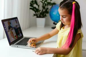 de bonne humeur Jeune peu fille avec une animal de compagnie hamster en utilisant portable ordinateur en train d'étudier par en ligne e-learning système à maison. distance ou éloigné apprentissage photo