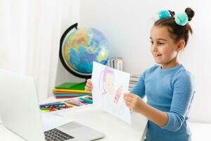 retour à école. en ligne éducation. intelligent école fille dans Salle de classe. enfance étude en ligne. dessin leçon. connaissance journée. petit fille élève avec portable. dessiner image avec marqueur. vivant dans numérique âge. photo