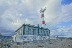 une phare sur le rive de une rocheux zone photo