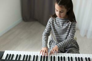 jolie petite fille joue au piano, synthétiseur. entraînement. éducation. l'école. formation esthétique. classe élémentaire. photo