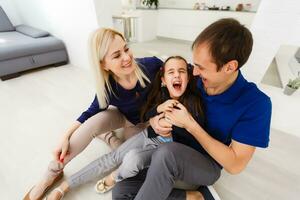 souriant Parents chatouillement préadolescent fille dans lit photo