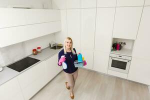 une femme est nettoyage le cuisine. elle est à la recherche une façon de le caméra. horizontalement encadré tir. photo