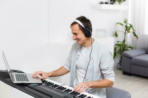 une homme apprentissage à jouer piano en ligne avec une ordinateur rester à maison. concepts de soi enseigné, rester à Accueil et travail en ligne photo