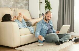 homme en portant café tasse tandis que le épouse est en train de lire une livre. photo