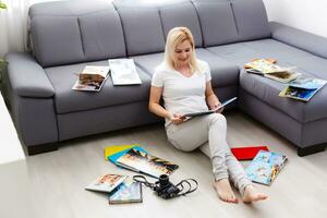 Jeune content femme à la recherche à livre photo dans sa pièce