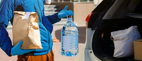 livraison homme en portant papier sac avec nourriture près le voiture, nourriture livraison homme dans protecteur masque photo