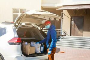 livraison homme en portant papier sac avec nourriture près le voiture, nourriture livraison homme dans protecteur masque photo