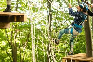 adorable peu fille profiter sa temps dans escalade aventure parc sur chaud et ensoleillé été journée. photo