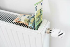 billet de banque mensonge sur le radiateur, le concept de en hausse énergie des prix et plus coûteux chauffage photo