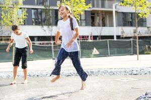 la vie de les enfants dans une moderne ville peu fille ayant amusement avec fontaines photo