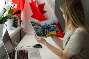 une femelle main détient une petit Canada drapeau et une portable sur le Contexte de le université. proche en haut photo