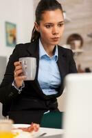 indépendant femme d'affaires recherche sur l'Internet et profiter le café. concentré affaires femme dans le Matin multitâche dans le cuisine avant Aller à le bureau, stressant façon de vie, carrière et buts à rencontrer. photo