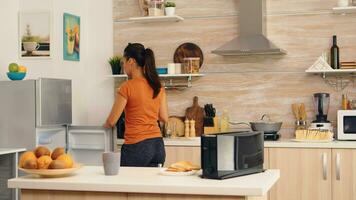 femme prise en dehors des œufs de frigo dans le Matin pour petit déjeuner. femme au foyer avoir impuissant des œufs et autre Ingrédients de réfrigérateur dans sa cuisine. photo