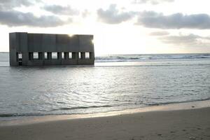 les pièces de béton bâtiment à le plage de le mer ai génératif photo
