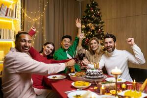 diverse copains souriant et à la recherche à caméra groupe de gens célébrer Nouveau année et Noël à Accueil séance sur Noël dîner et en buvant vin, portrait de content gens sur vacances. photo