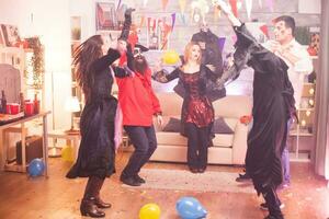 groupe de copains dansant avec mains en haut tandis que célébrer Halloween dans leur déguisements. photo