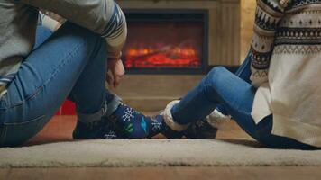 Jeune couple avec chaud chaussettes dans de face de cheminée célébrer Noël. photo