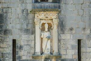 une statue de une homme sur une mur dans une pierre bâtiment photo