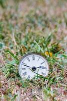 un vieux l'horloge pose dans le herbe photo