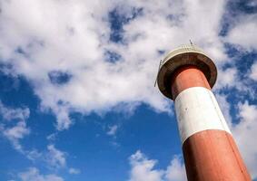 une rouge et blanc phare la tour contre une bleu ciel photo