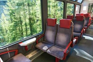 à l'intérieur de électrique train avec rouge siège sur chemin de fer qui passe le vallée dans Suisse Alpes photo