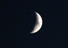 lune moitié couvert par ombre dans le noir ciel. photo