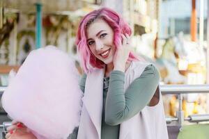 rose cheveux fille court la Coupe de cheveux posant dans amusement parc sur carrousel Contexte. photo