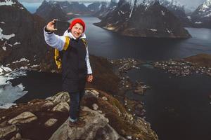 Homme voyageur prenant une photo d'autoportrait avec un smartphone en randonnée sur la crête de la montagne en Norvège