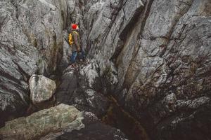 homme voyageur avec un sac à dos jaune portant un chapeau rouge debout sur le fond des rochers. concept de mode de vie de voyage photo