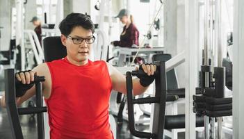 homme asiatique musclé fort entraînement dans la salle de gym faisant des exercices au biceps. concept de musculation.