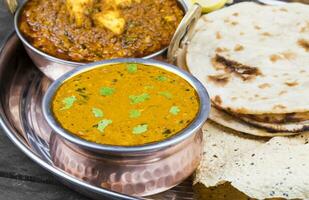 Indien traditionnel thali nourriture dal makhani servi avec chapati, papad, kadai paneer ou citron sur ancien en bois Contexte photo