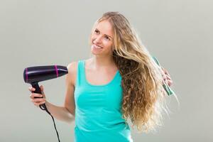 Jeune femme avec magnifique longue blond cheveux en utilisant Sèche-cheveux. photo