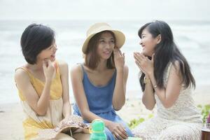 plus jeune asiatique femme ami relaxant parlant avec bonheur émotion à vacances mer plage photo