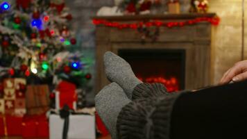 proche en haut de femme pieds relaxant sur copain les genoux sur Noël journée séance sur canapé. Noël couple la magie confortable chaud cheminée, dépenses de fête vacances ensemble dans famille photo