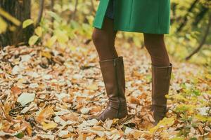 proche en haut photo de femme dans bottes entouré avec tomber feuillespendant dépenses temps dans le parc.