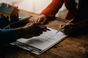 agent de courtage immobilier présentant et consultant le client pour la prise de décision signant un accord de formulaire d'assurance, modèle d'achat et de vente de maison, concernant l'offre de prêt hypothécaire et l'assurance habitation photo