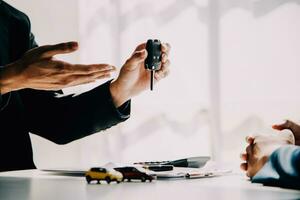 une voiture de location entreprise employé est remise en dehors le voiture clés à le loueur après discuter le de location détails et conditions ensemble avec le loueur signature une voiture de location accord. concept voiture de location. photo