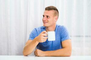 Jeune homme jouit en buvant café à maison. photo