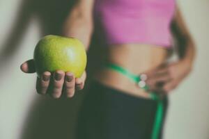 en forme femme mesure sa mince taille avec une ruban mesure et en portant pomme.focus sur Pomme. photo