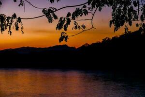 le Soleil ensembles plus de une Lac avec montagnes dans le Contexte photo