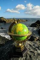 une globe sur une Roche près le océan photo