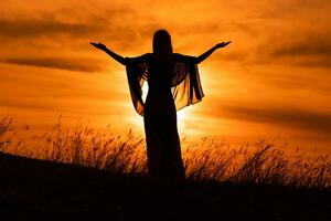 silhouette de une femme avec bras tendu à la recherche à magnifique le coucher du soleil. photo