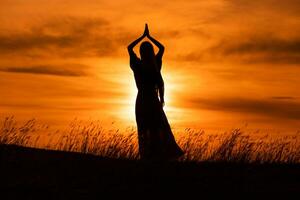 silhouette de une femme jouit méditer à magnifique le coucher du soleil. photo