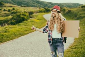 magnifique Jeune femme en portant Vide papier carton et auto-stop à le pays route.tonique image. photo