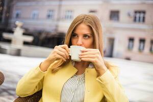 magnifique Jeune femme jouit en buvant café à le ville. photo